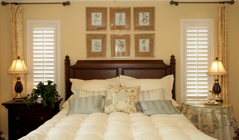Bedroom with two tall plantation shutters on either side of bed in Miami 